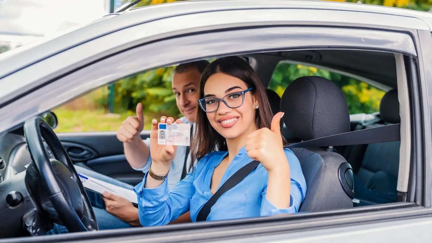 Señora feliz alzando su brevete de conducir dentro de un auto