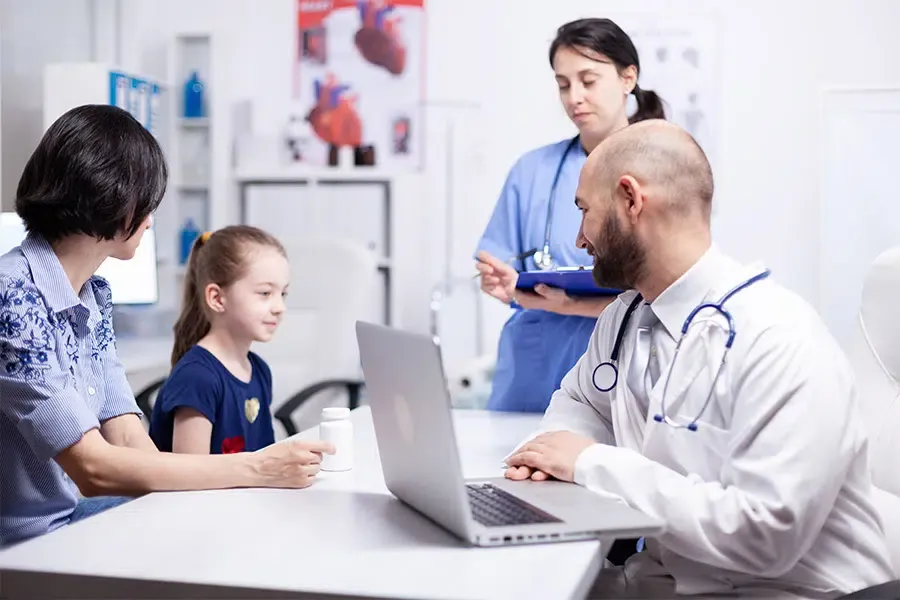 Médico general le está dando instrucciones a una niña con su madre al lado