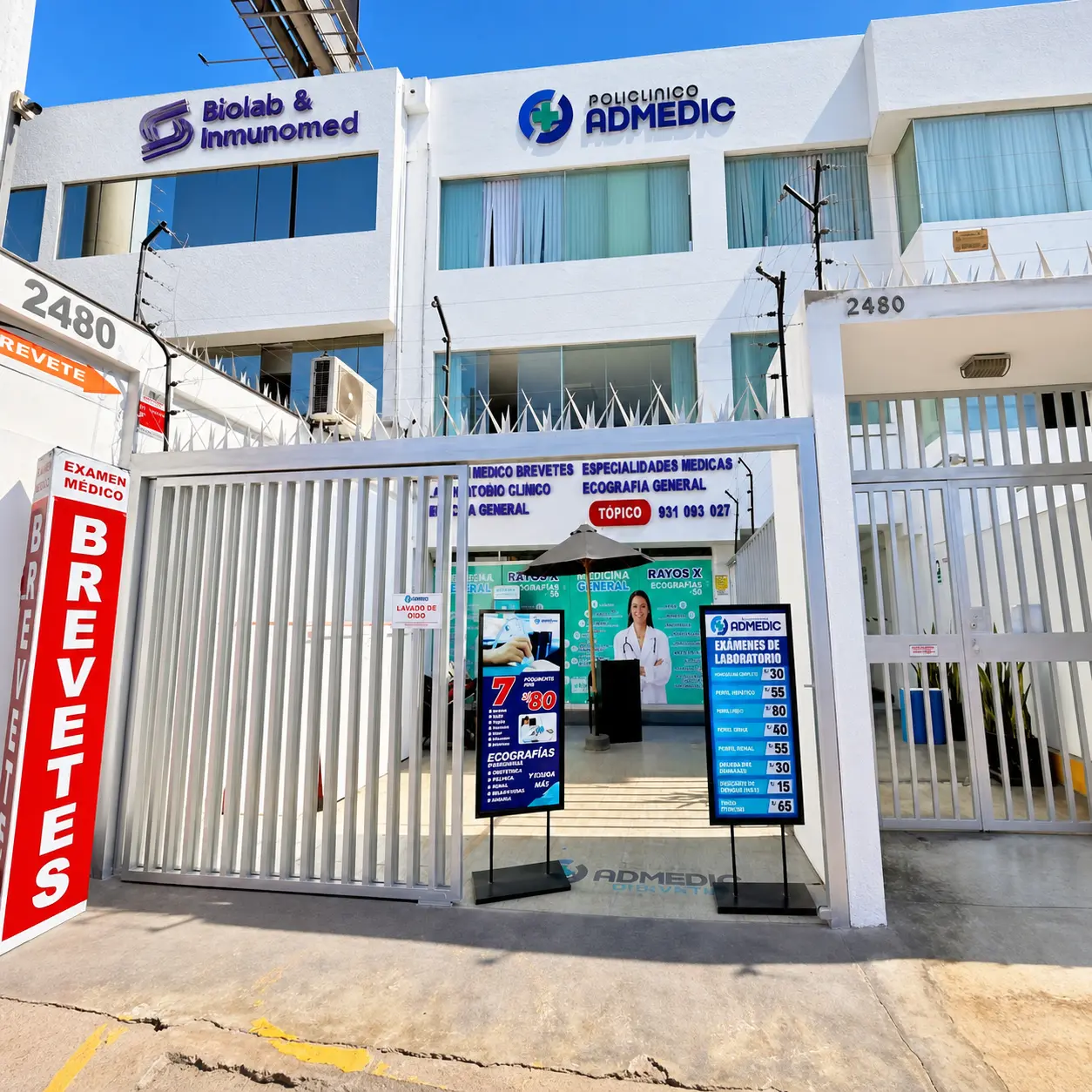 Fachada exterior e ingreso principal del Policlínico Admedic con lista de especialidades médicas.